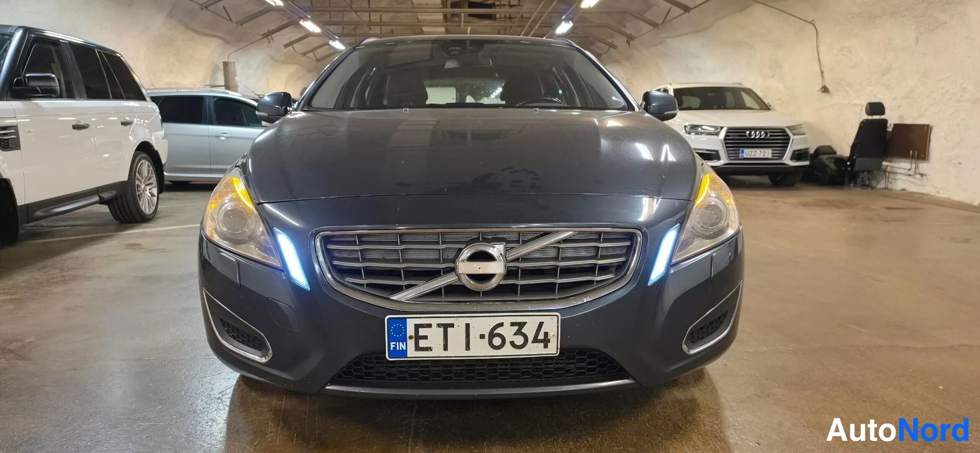 Edestä: Volvo V60:n etupää edestä kuvattuna, rekisterikilpi, tummanharmaa kori.