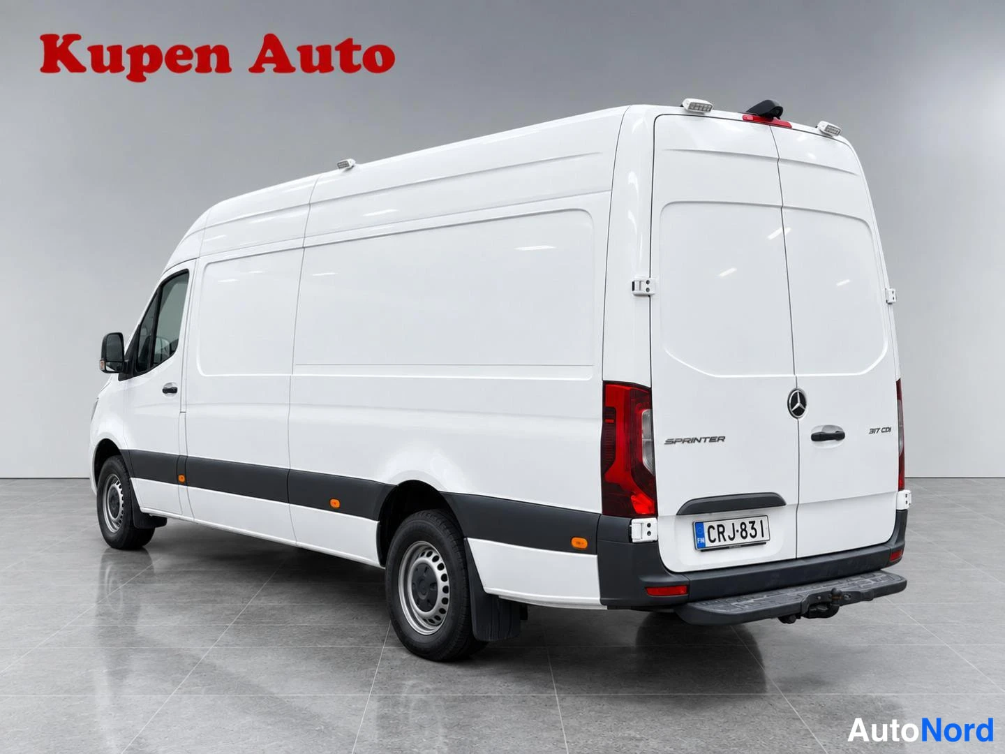 Takaviisto: Valkoinen Mercedes-Benz Sprinter -pakettiauto taka­viistosta oikealta, moottoritien varrella ei; studiovalo, rekisteritunnus.
