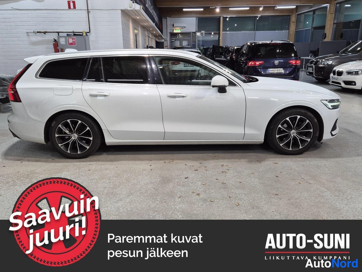 Etuviisto, nokka oikealle: Valkoinen farmariauto sivukulmassa oikealta nähtynä, keulan etuvalo näkyy kuvan oikeassa reunassa.
