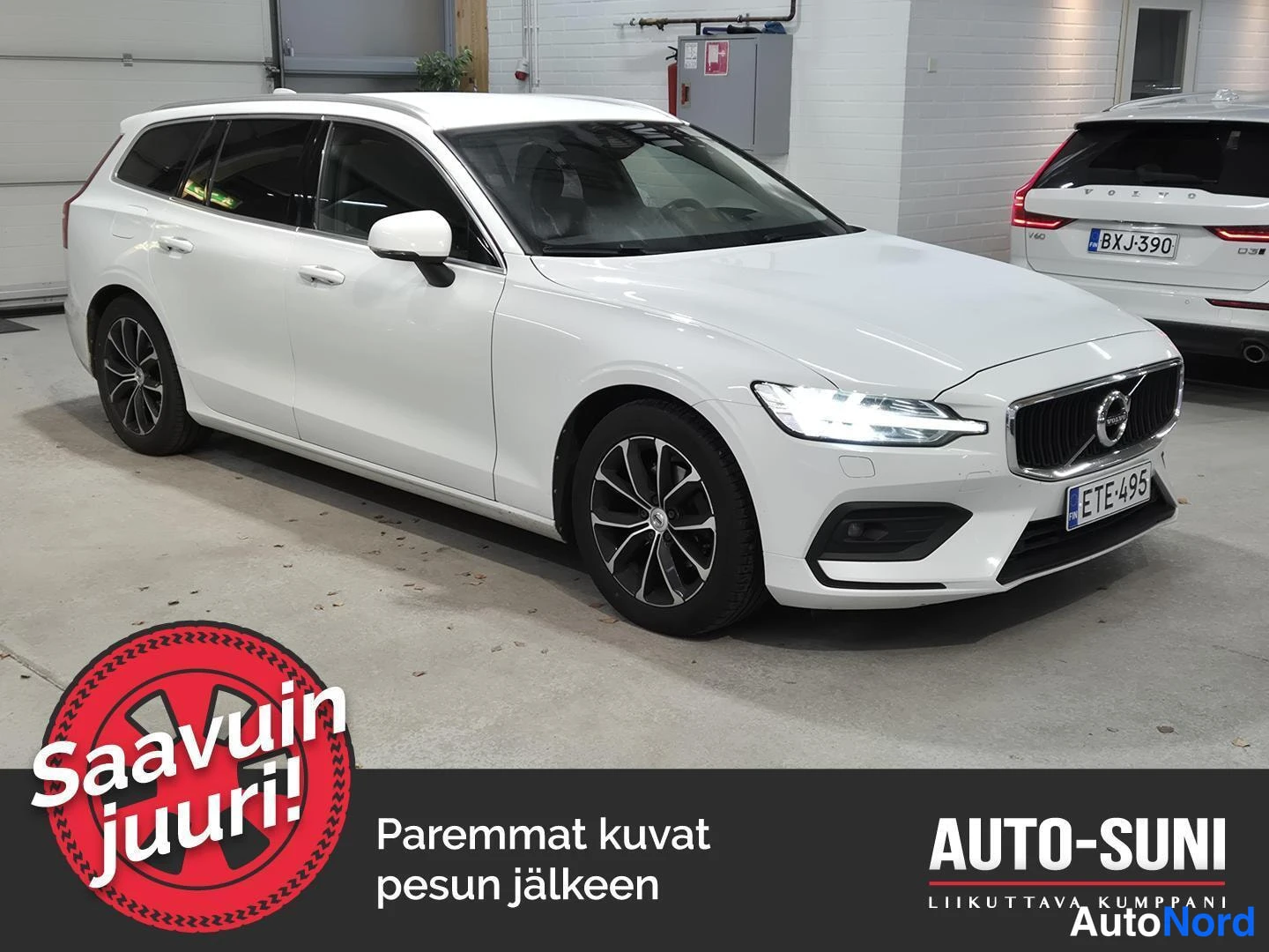 Etuviisto, nokka oikealle: Valkoinen farmariauto kolmesta neljäsosasta etuosasta oikealle, kuva tallissa.
