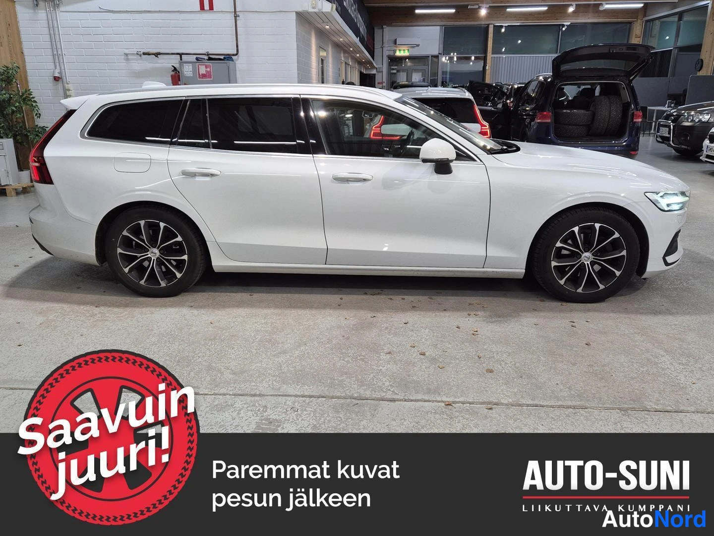 Etuviisto, nokka oikealle: Valkoinen farmariauto sivusta oikealta, kuva autotallissa.