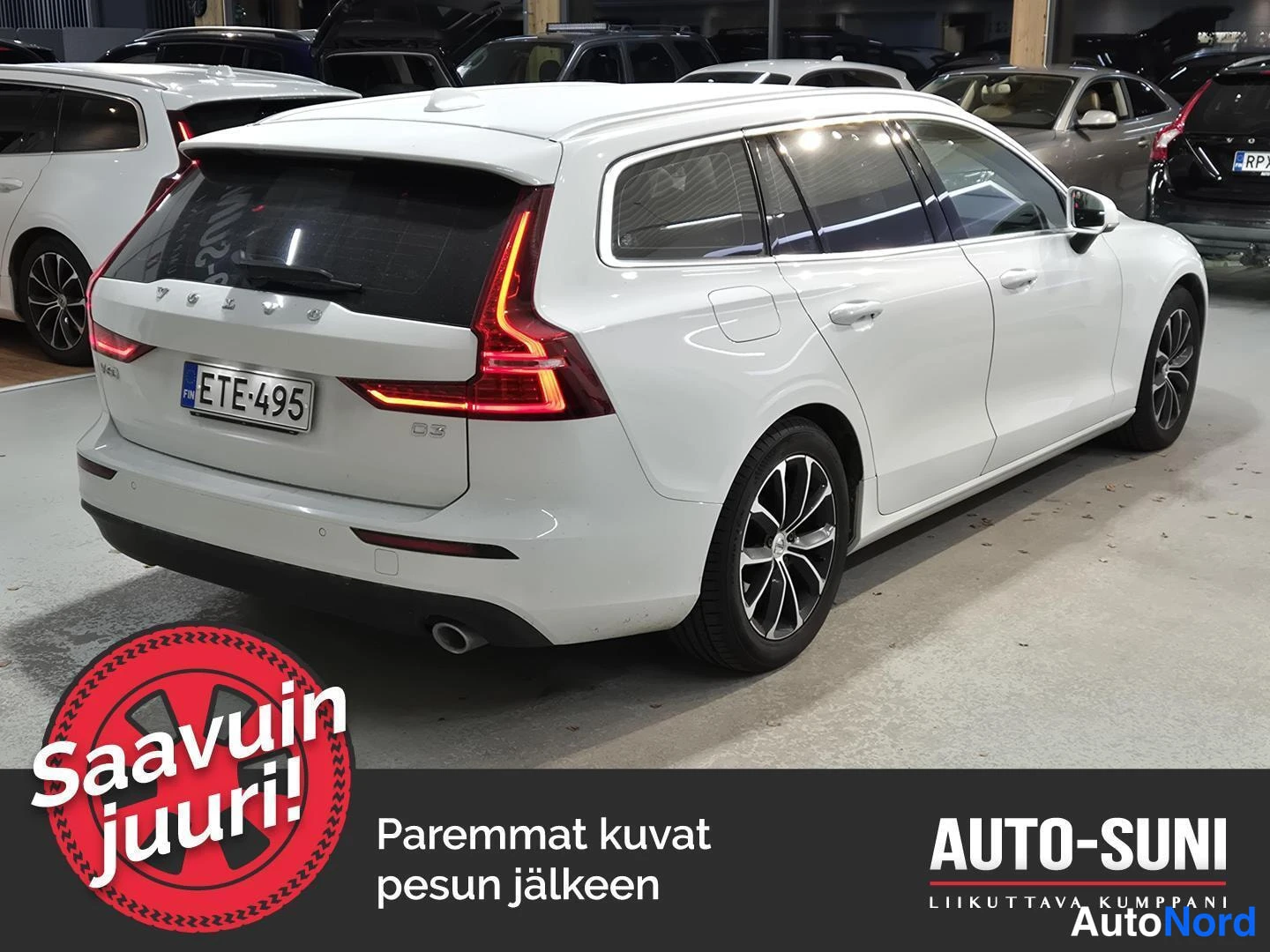Takaviisto: Valkoisen farmariauton takaosa ja sivu, rekisterikilpi, kuva autotallissa.