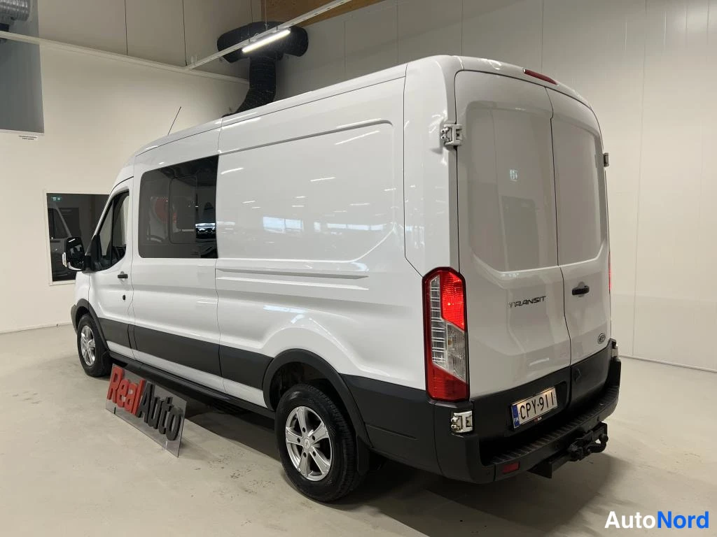 Takaviisto: Valkoinen pakettiauto takaa sivulta kuvattuna sisätilassa, rekisteritunnus ja kyljessä RealAuto-kyltti.