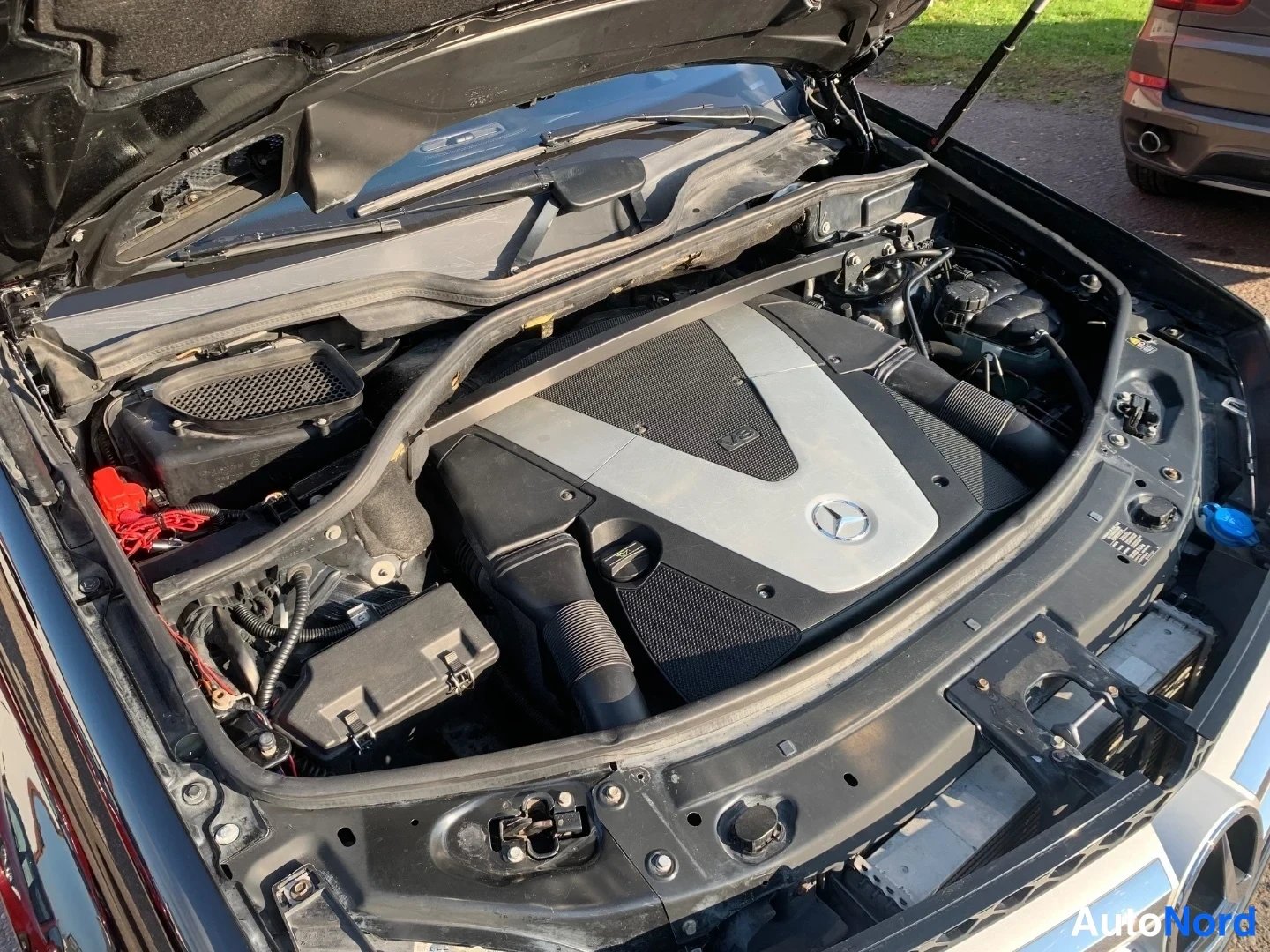 Muu: Mercedes-Benzin V8-moottoritila konepellin alla, kansipelti Mercedes-merkillä.