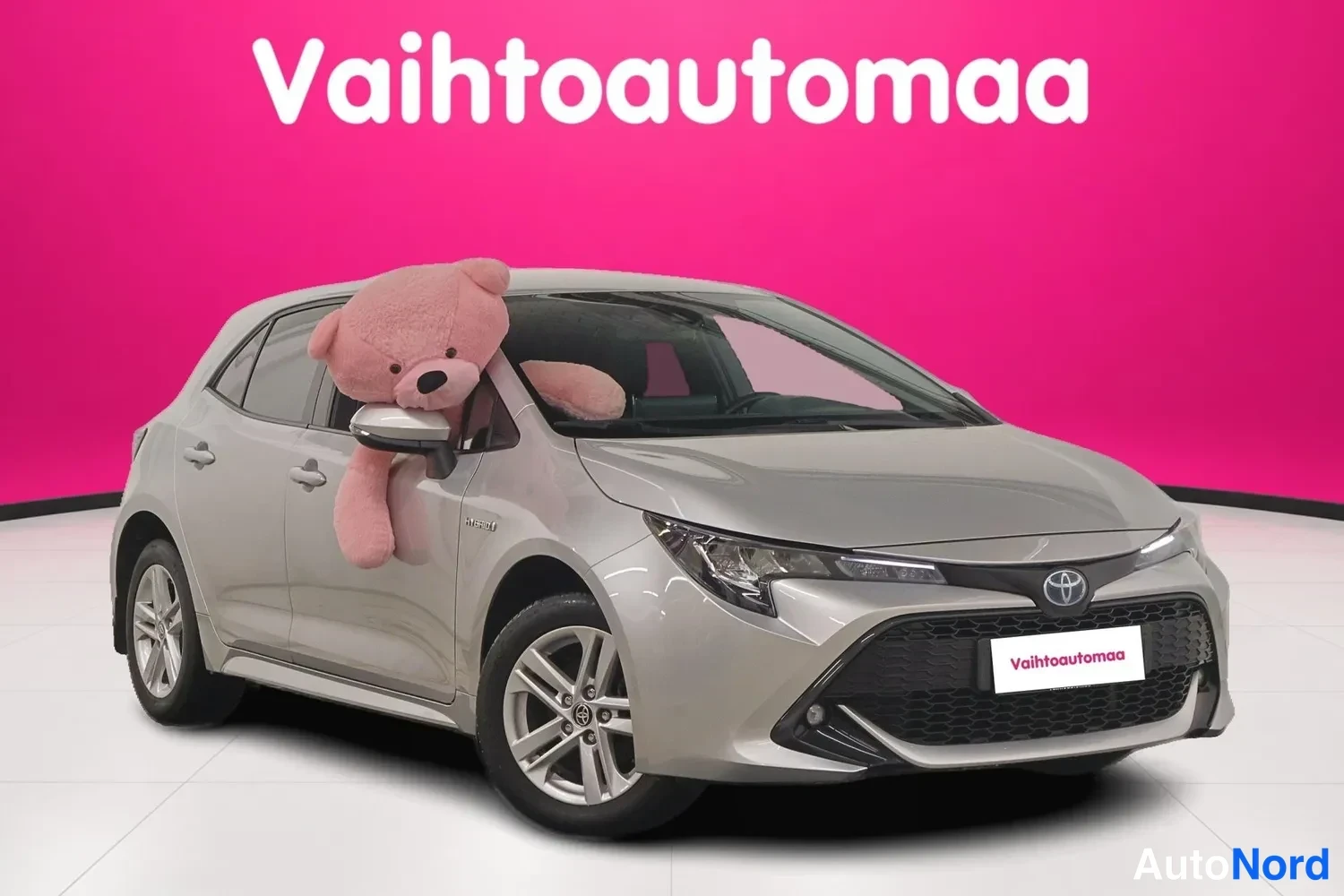 Etuviisto, nokka oikealle: Toyota Corolla -viistokuva edestä oikealta, hopeanharmaa auto pinkillä taustalla