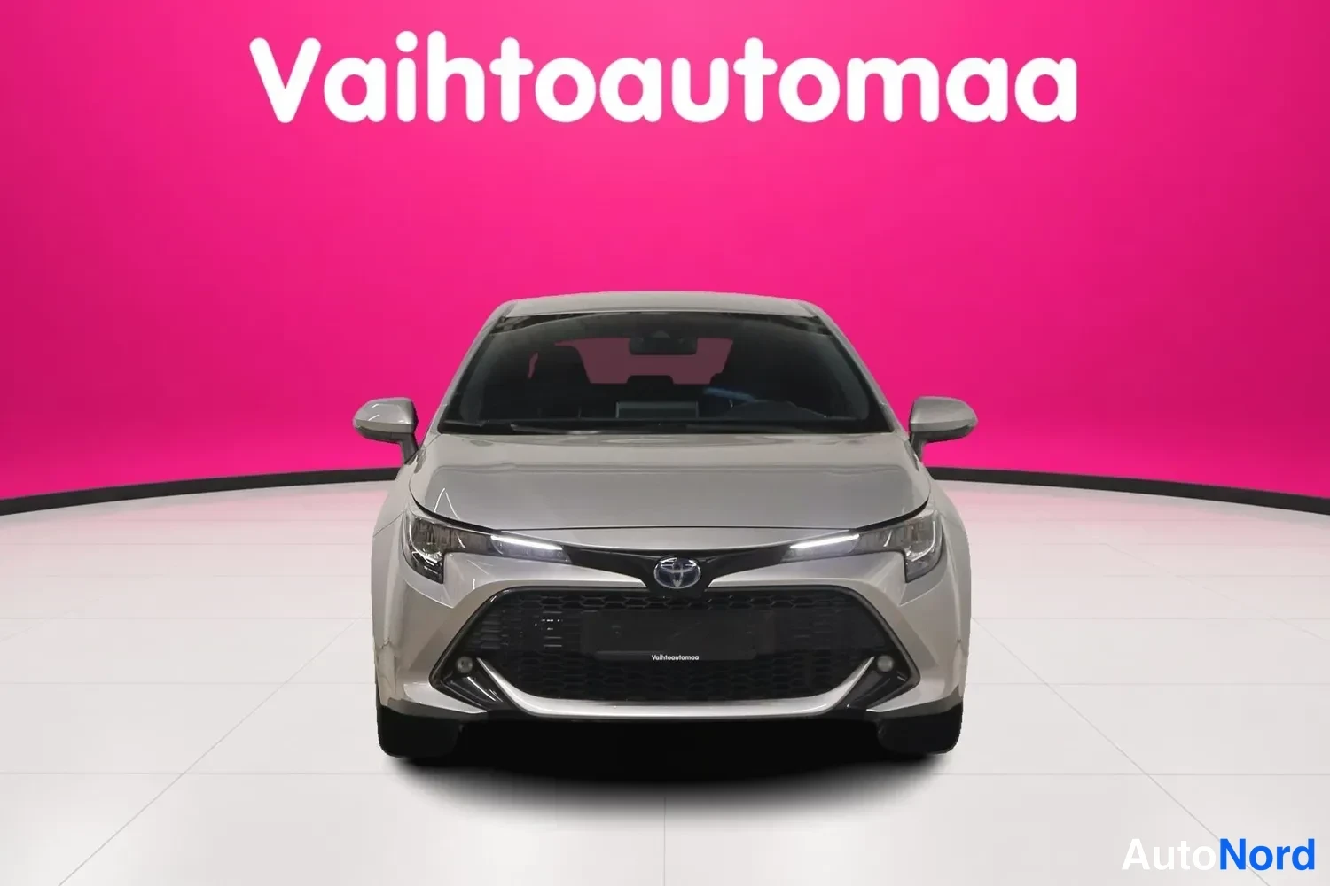 Edestä: Toyota Corolla suoraan edestä kuvattuna, pinkki studiovausta