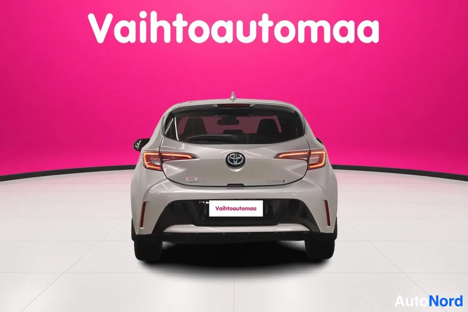 Takaa: Auton takaosa suoraan takaa, valkoinen viistoperä,Toyota-merkki ja takaoverride hyvin näkyvissä.