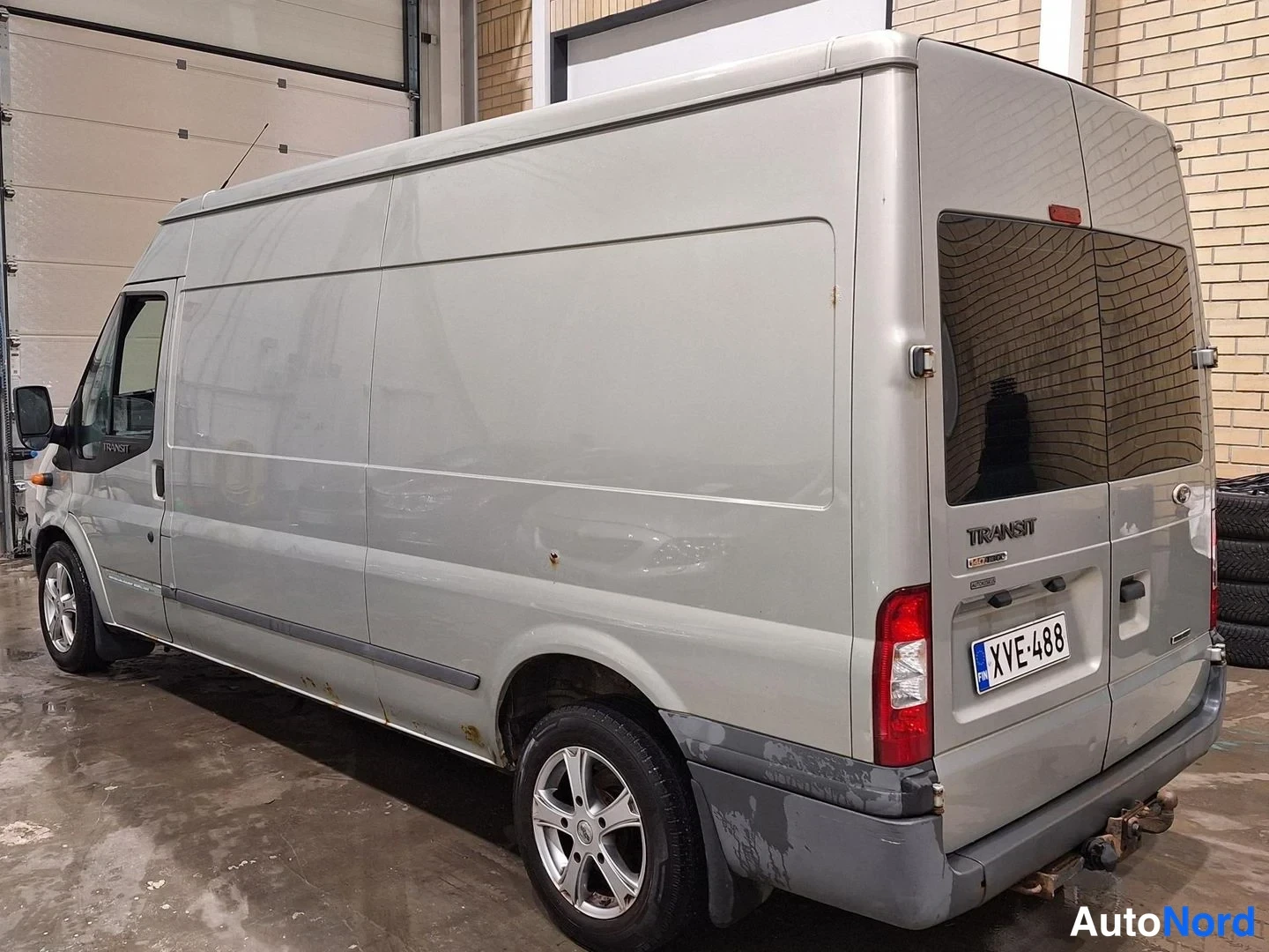 Takaviisto: Sivulta-taakse kuvattu Ford Transit -pakettiauto, korin vasen kylki ja takaluukku, Ford-merkki ja Transit-tarra näkyvät.