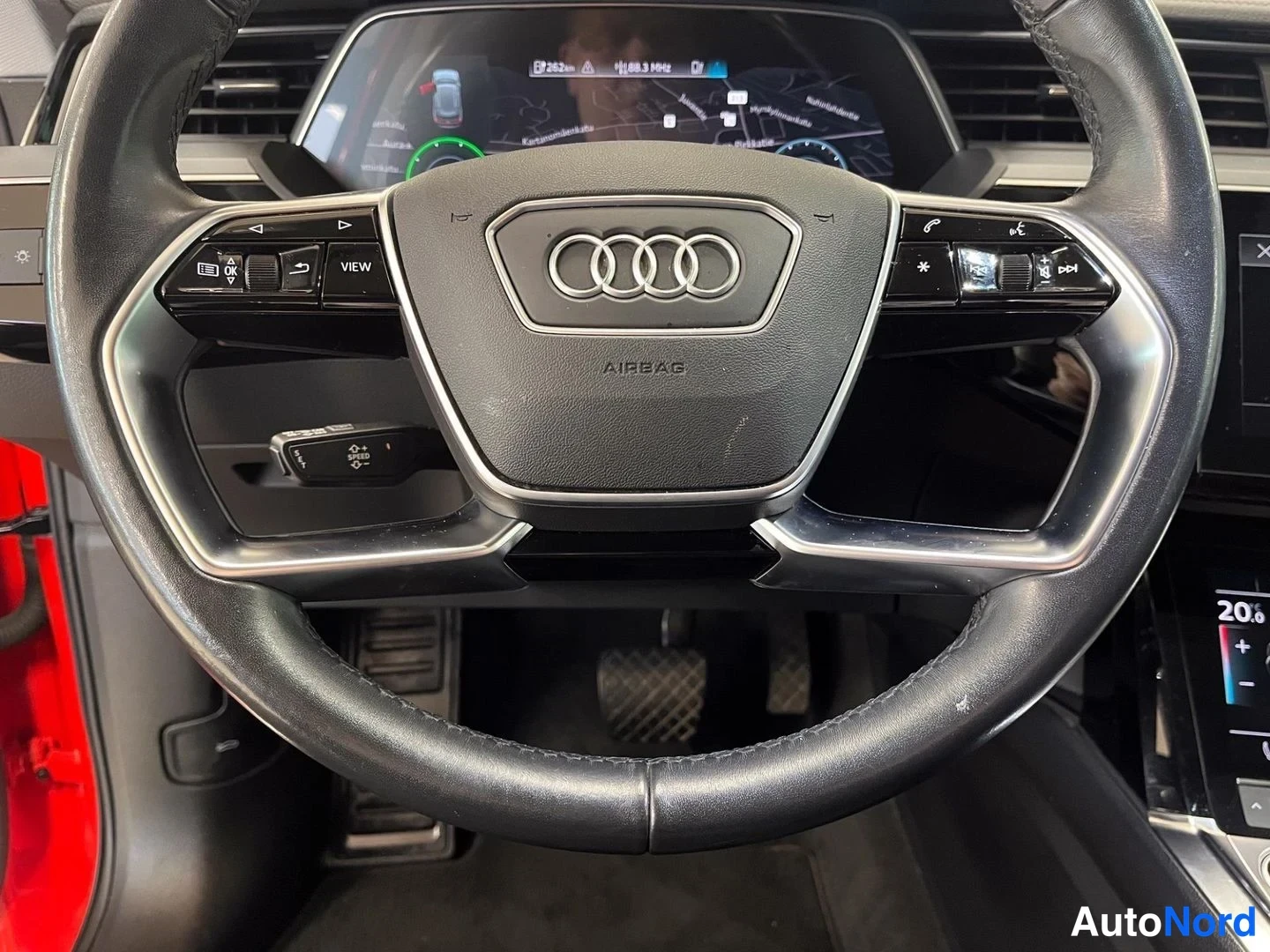 Edestä: Ohjaamon näkymä: Audi-muiltiteeringonaapí ja kojelautanäyttö kartalla taustalla.