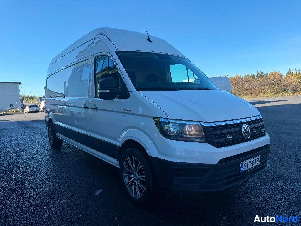 Etuviisto, nokka oikealle: Valkoinen Volkswagen Crafter -pakettiauto etukulmasta vasemmalla puolella, rekisteritunnus.