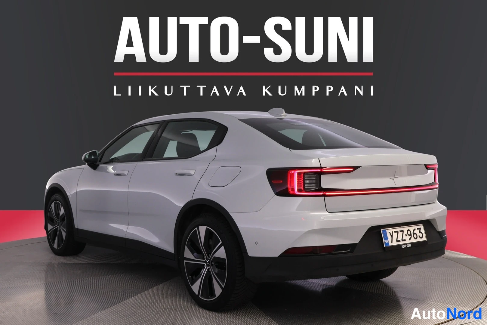 Takaviisto: Valkoinen Polestar 2 takaviistosta oikealta, rekisteritunnus, LED-takavalot syttyneenä.