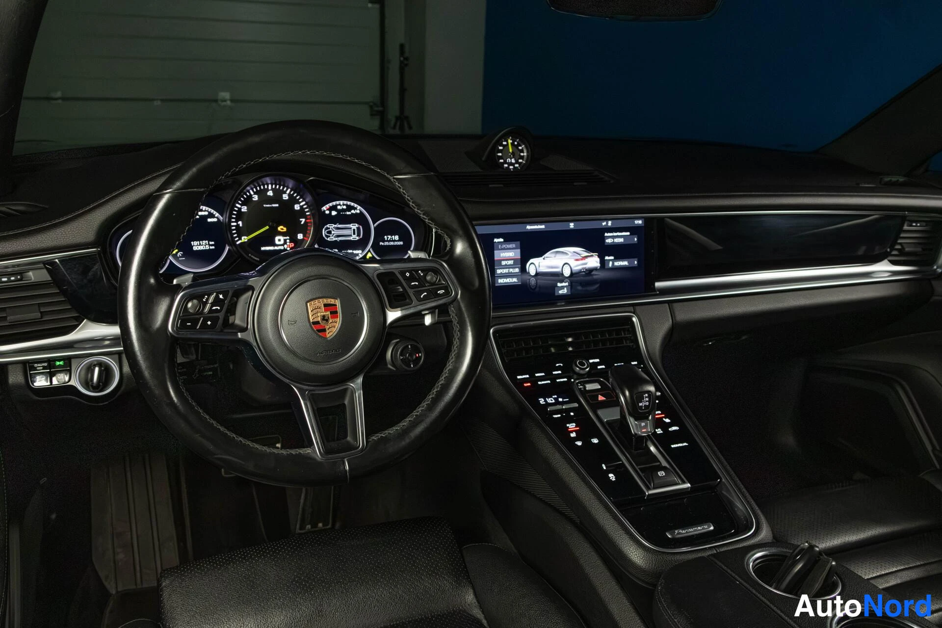 Sivulta: Porsche Panamera 4 E-Hybridin kuljettajan puolen sisätilat: ohjauspyörä ja mittaristo, kosketusnäyttö keskikonsolissa ja automaattivaihteen valitsin.