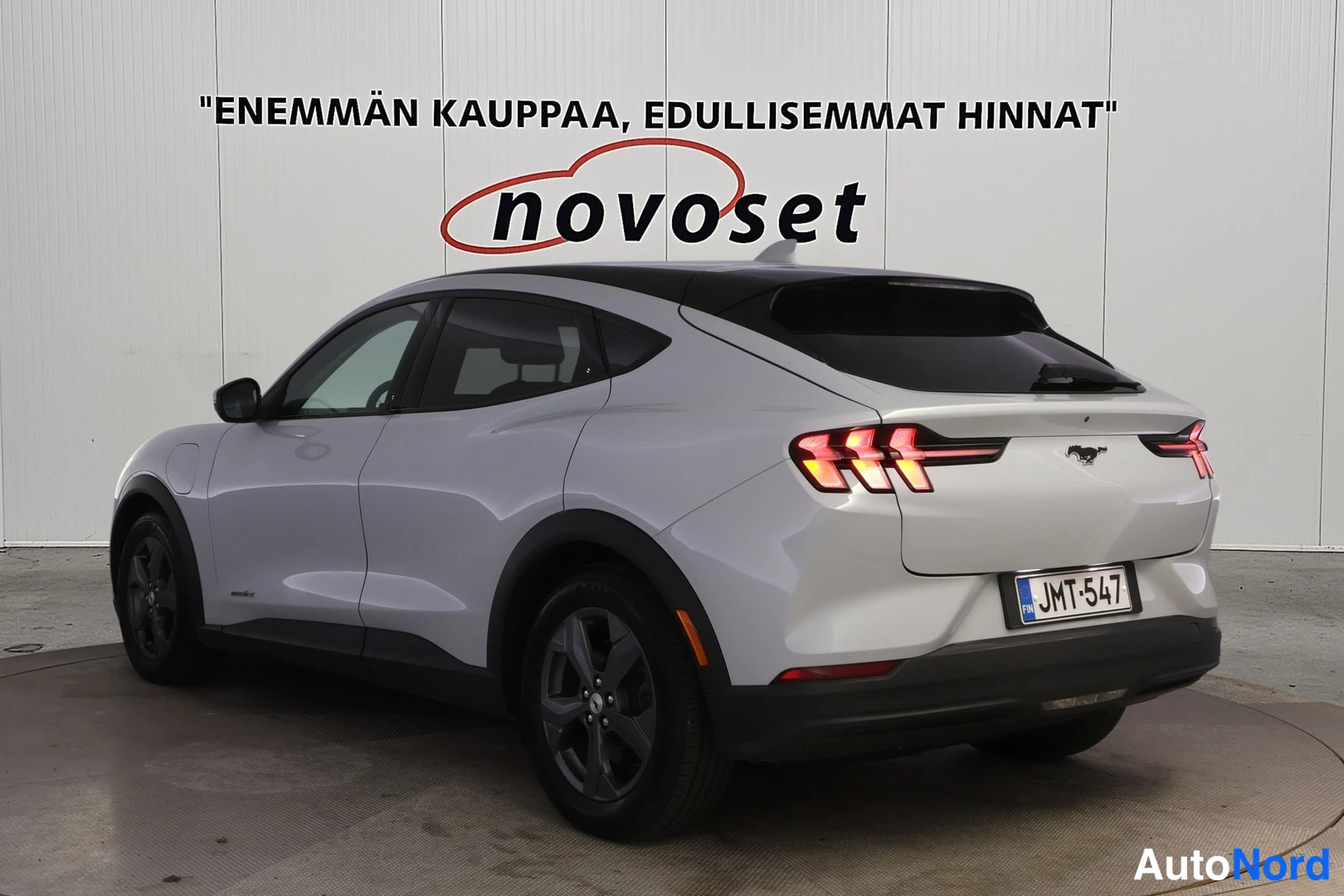 Takaviisto: Valkoisen Ford Mustang Mach-E:n takakulmanäkymä, musta katto ja tummat takavalot, rekisteritunnus.