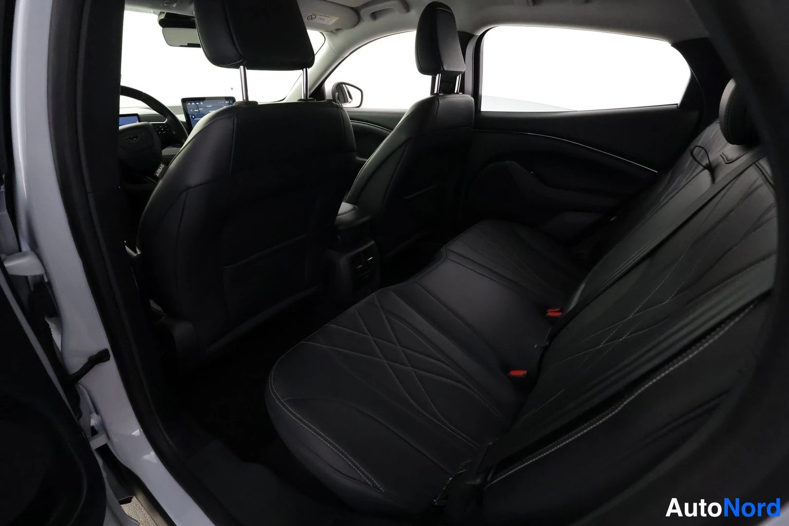 Takaistuimet: Mustang Mach-E:n takaistuimelta näkymä: mustat nahkaiset istuimet, etuistuimet ja osa kojelaudasta ja infotainment-näytöstä näkyvät.