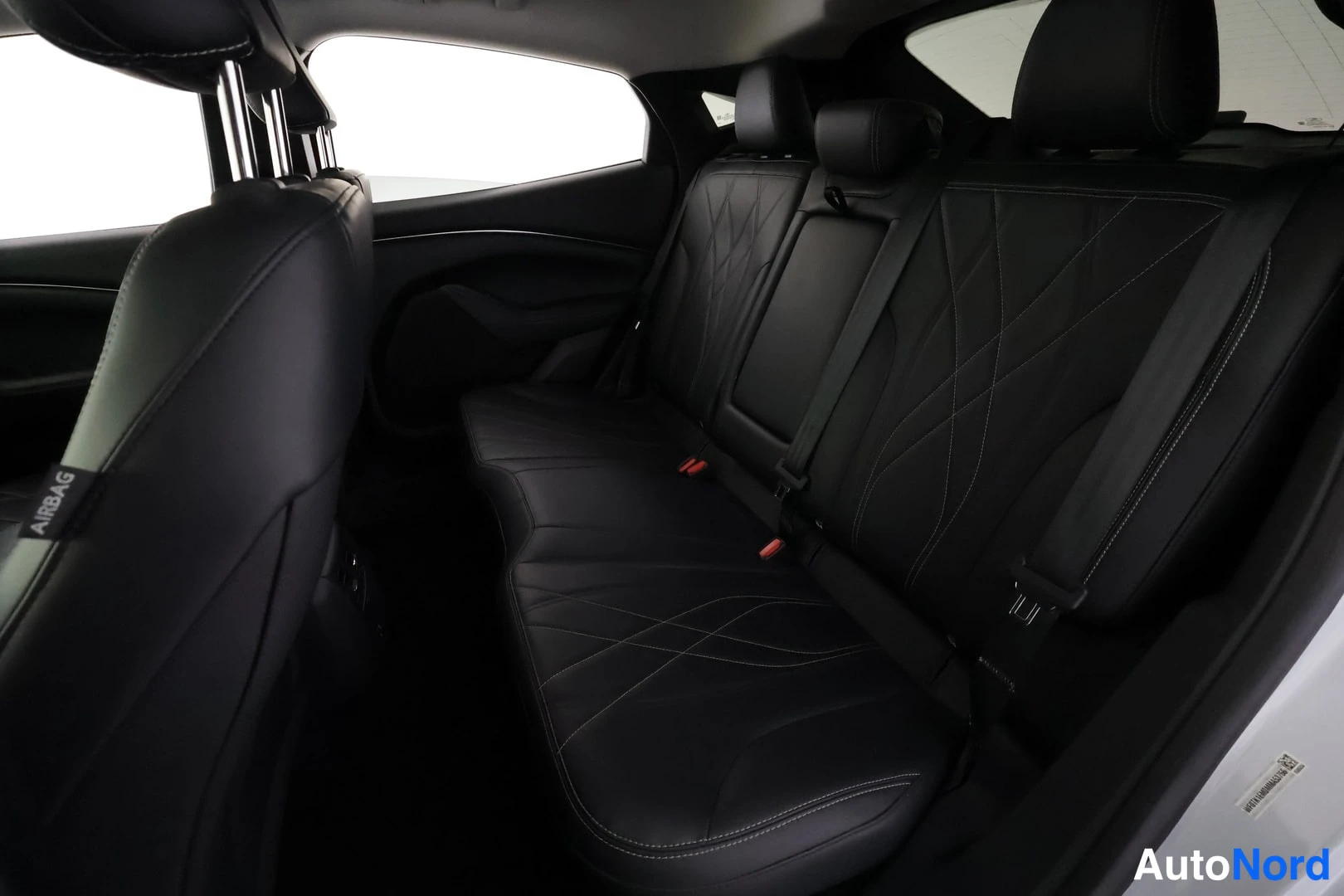 Takaistuimet: Mustang Mach-E:n takaistuimet ja matkustamon takanurkka, mustat nahkaiset istuimet ja AIRBAG-tekstitarrat B-pilareissa.