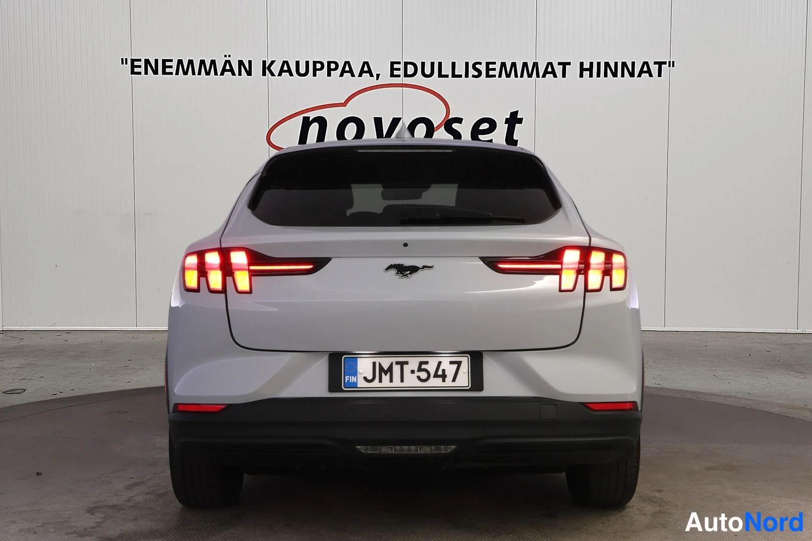 Takaa: Valkoisen Ford Mustang Mach-E:n suora takaosa, tummat takavalot, rekisteritunnus.