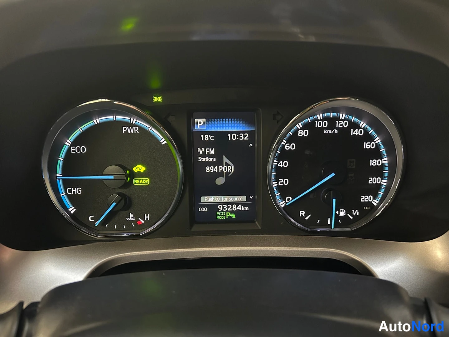 Yksityiskohta: Mittaristo: hybridivalot READY ja EV, matkamittari 93284 km, nopeusmittari ja näyttö jossa radio ja lämpötila 18 °C.