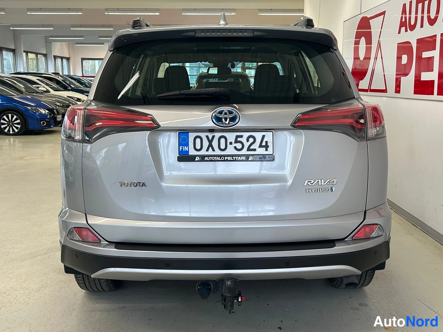 Takaa: Suora takanäkymä hopeanvärisestä Toyota RAV4 Hybrid -autosta, rekisterikilpi ja vetokoukku näkyvissä.