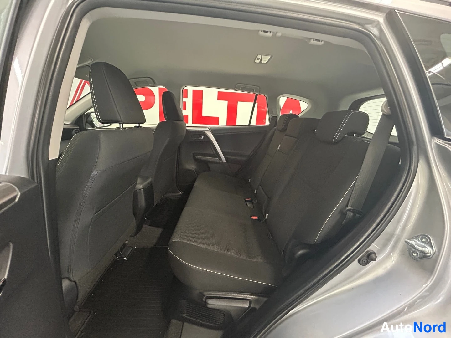 Muu: Sisäkuva Toyota RAV4:n takaistuimista takaa avatun oven kautta: musta kangastakapenkki ja lattiamatat.