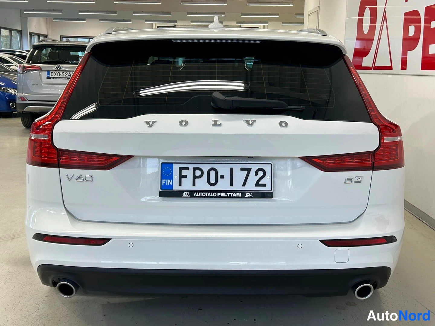 Takaa: Valkoisen farmariauton perä suoraan takaa, Volvo- ja V60-merkinnät, B3-merkintä, rekisterikilpi FP0-172, kaksoispakoputket.
