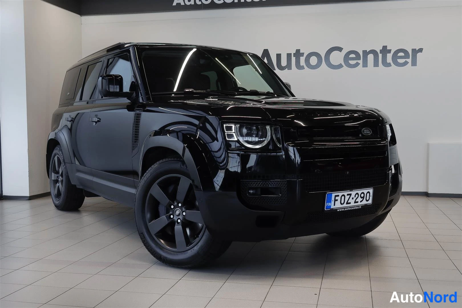 Etuviisto, nokka vasemmalle: Musta Land Rover Defender autohallissa, etukulmanäky vaaka-alueelta rekisterikilpi F0Z-290.