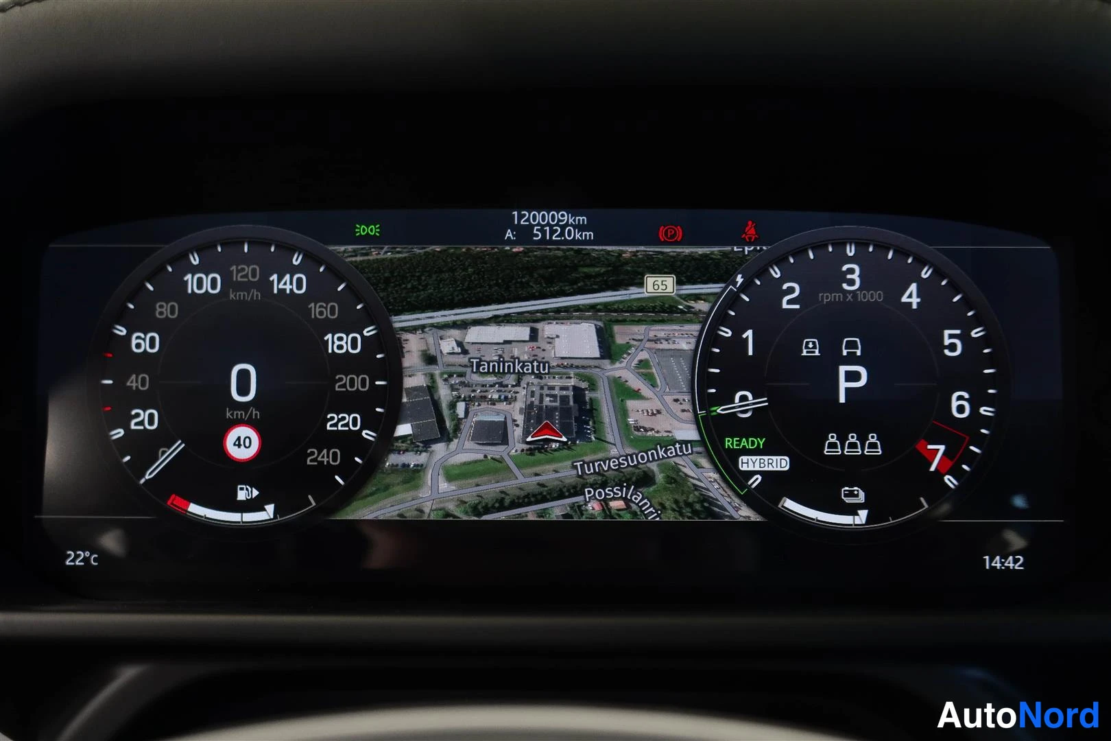 Muu: Kojelaudan mittariston lähikuva: kokonaislukuma 120009 km, paikkakunnan karttanäkymä ja valmis HYBRID-merkintä.