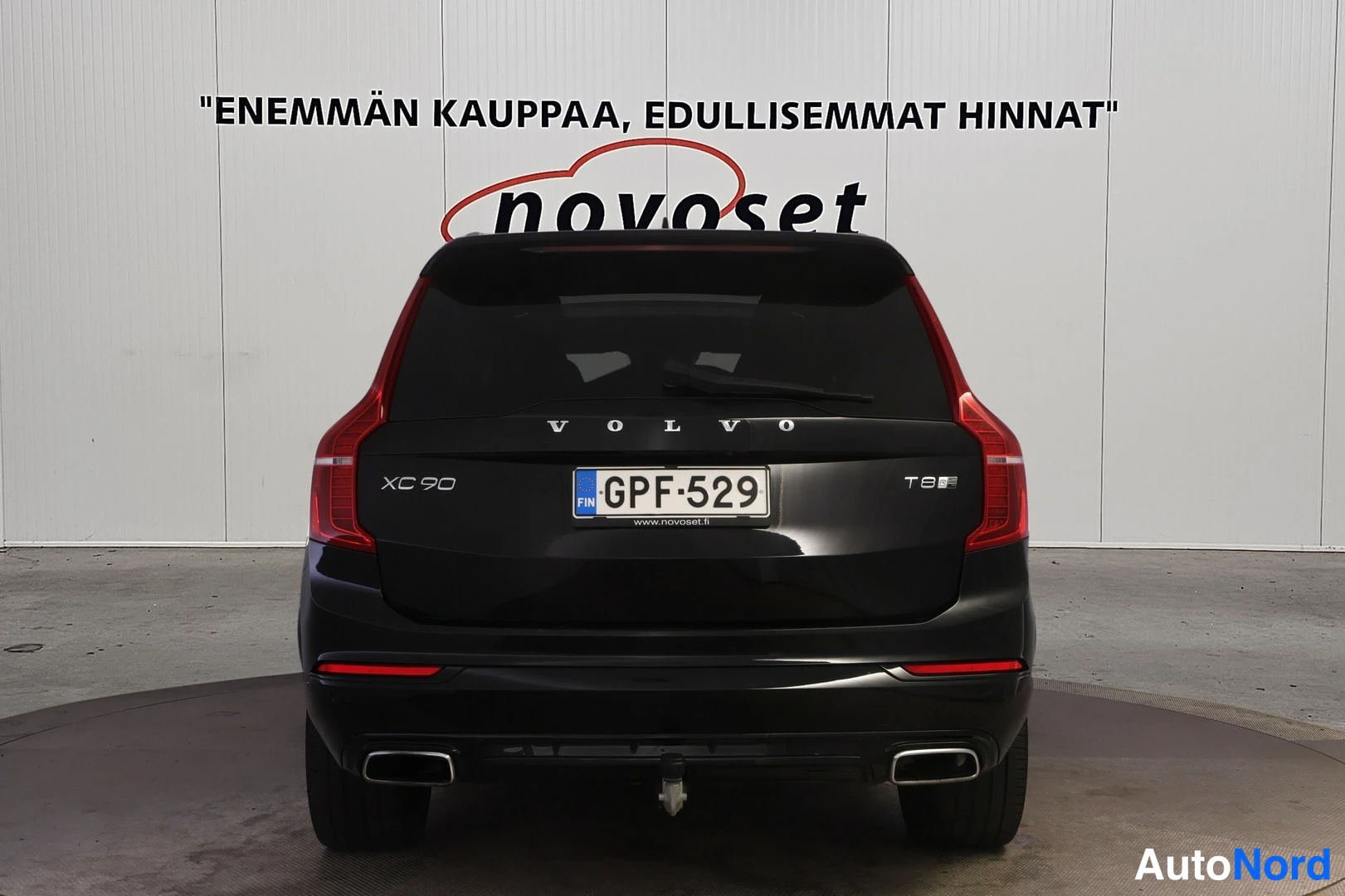 Takaa: Mustan Volvo XC90:n suora takaosa, XC 90- ja T8-merkinnät, rekisteritunnus ja kytkinveto takapuskurissa.