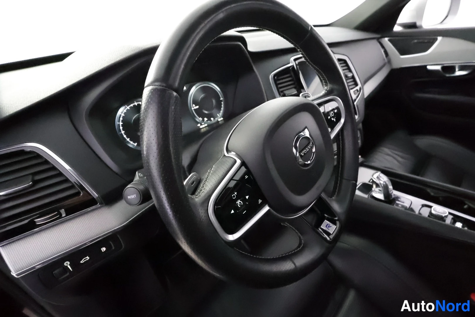Muu: Volvo-merkillinen ohjauspyörä, kojelauta, mittarit ja keskirivin hallintalaitteet; musta sisustus ja jalkatila takana.