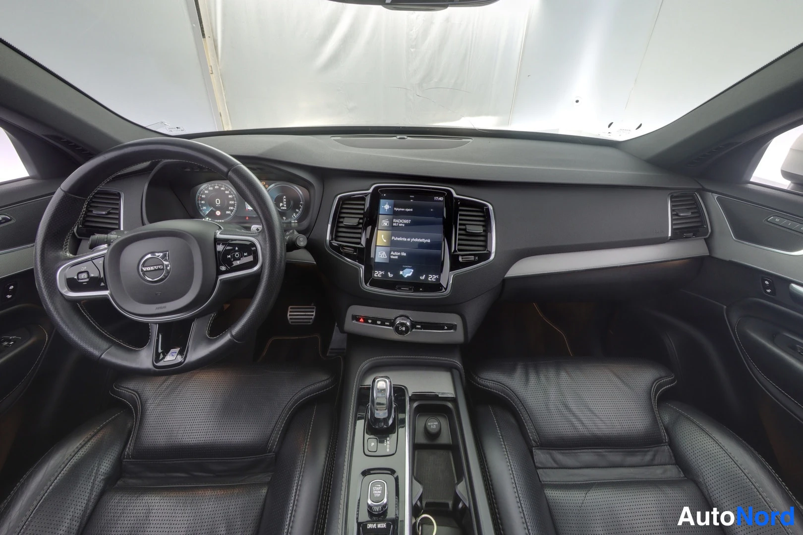 Muu: Volvo XC90:n ohjaamo ylhäältä: nahkaverhoillut etuistuimet, ohjauspyörä, keskikonsolin näyttö ja automaattivaihteen valitsin.
