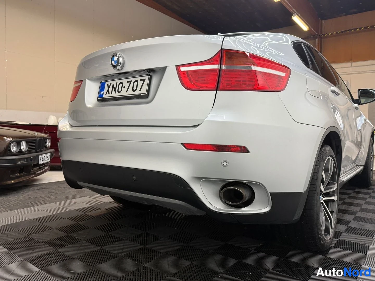 Takaviisto: BMW X6:n takaosan lähikuva; valkohopea kori, punaiset takavalot, rekisterikilpi, yksi näkyvä pakoputki.
