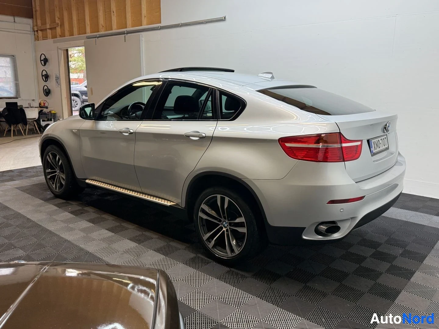 Takaviisto: BMW X6:n takaosa ja vasen kylki kolmelinjaisesta kulmasta; hopeinen kori, kattoluukku, sivustoimet, rekisterikilpi ja pakoputki näkyvät.