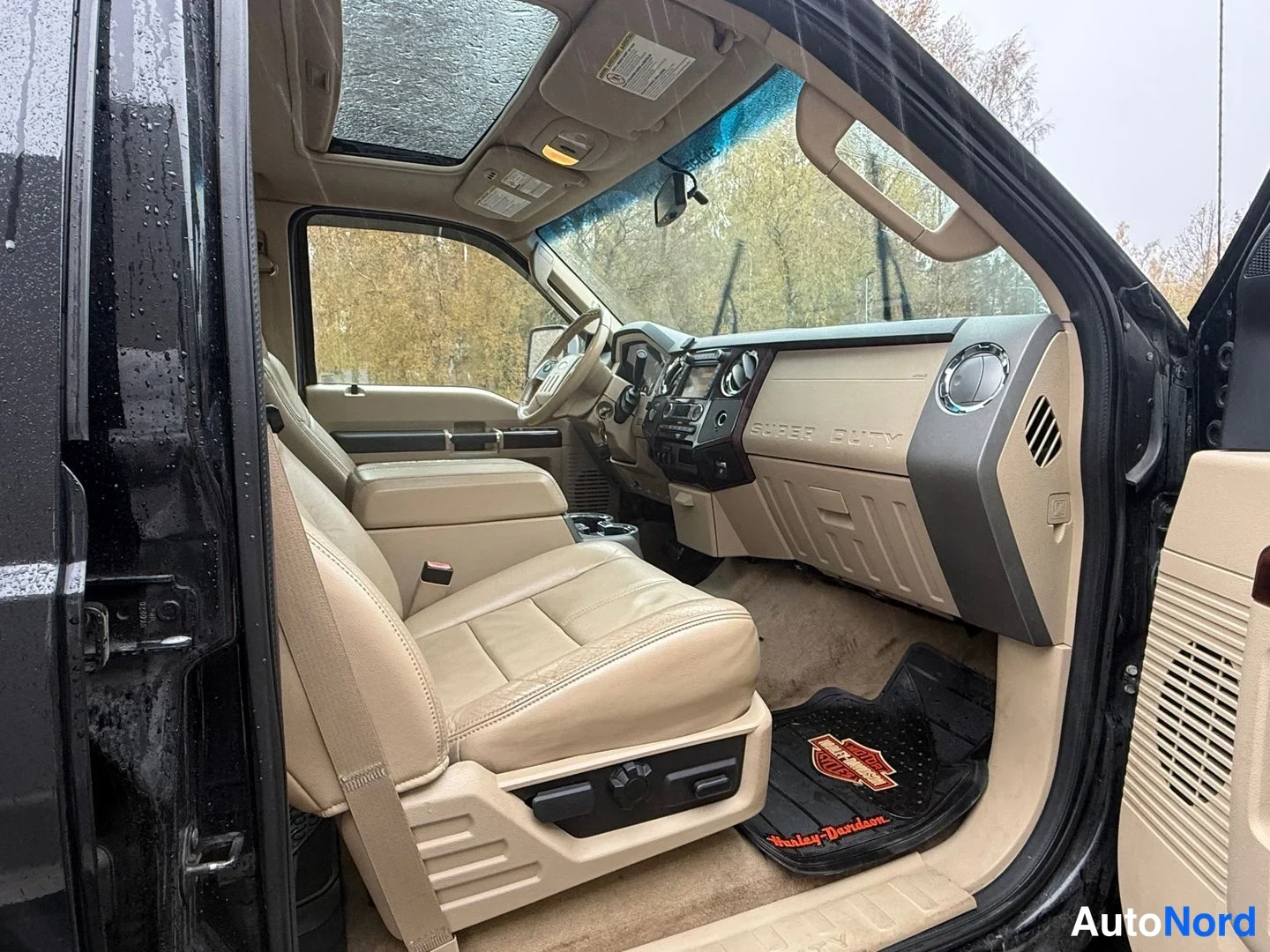 Muu: Kuljettajan puoli autossa: beigea nahkaa, mitat eivät ole saatavilla; oven avattu, kojelaudan 'Super Duty' -teksti näkyy