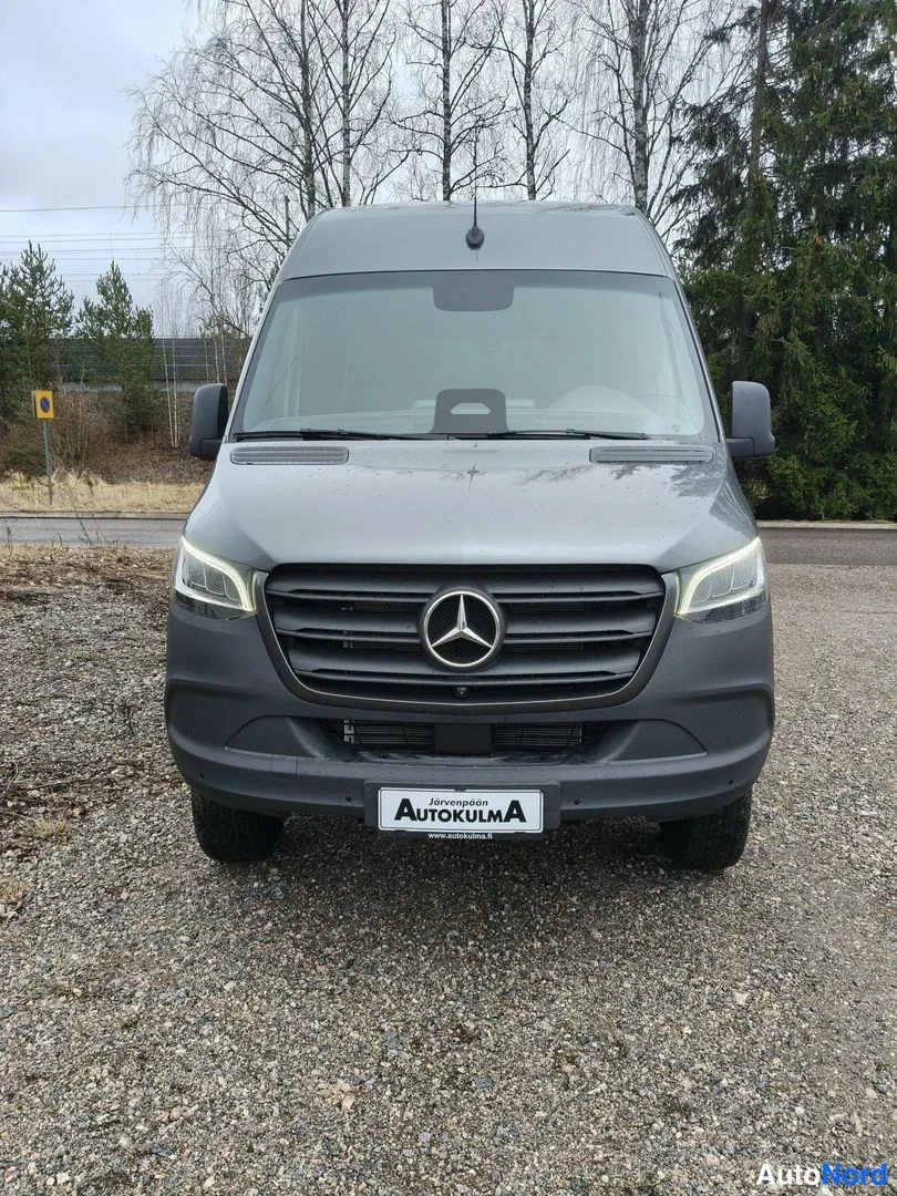 Edestä: Mercedes-Benz Sprinter -pakettiauto suoraan edestäpäin kuvattuna; harmaa keula, Mercedes-tähtimerkki ja AutoKulma-kilpi etupuskurissa.
