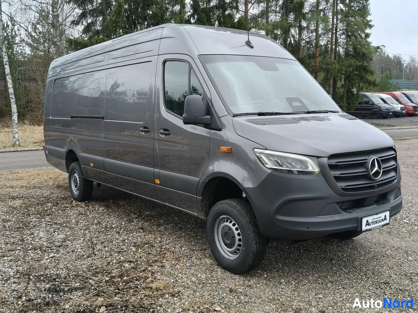 Etuviisto, nokka oikealle: Mercedes-Benz Sprinter -pakettiauto kulmasta edestä oikealta kuvattuna; tummanharmaa koripelti ja AutoKulma-tunnus etupuskurissa.
