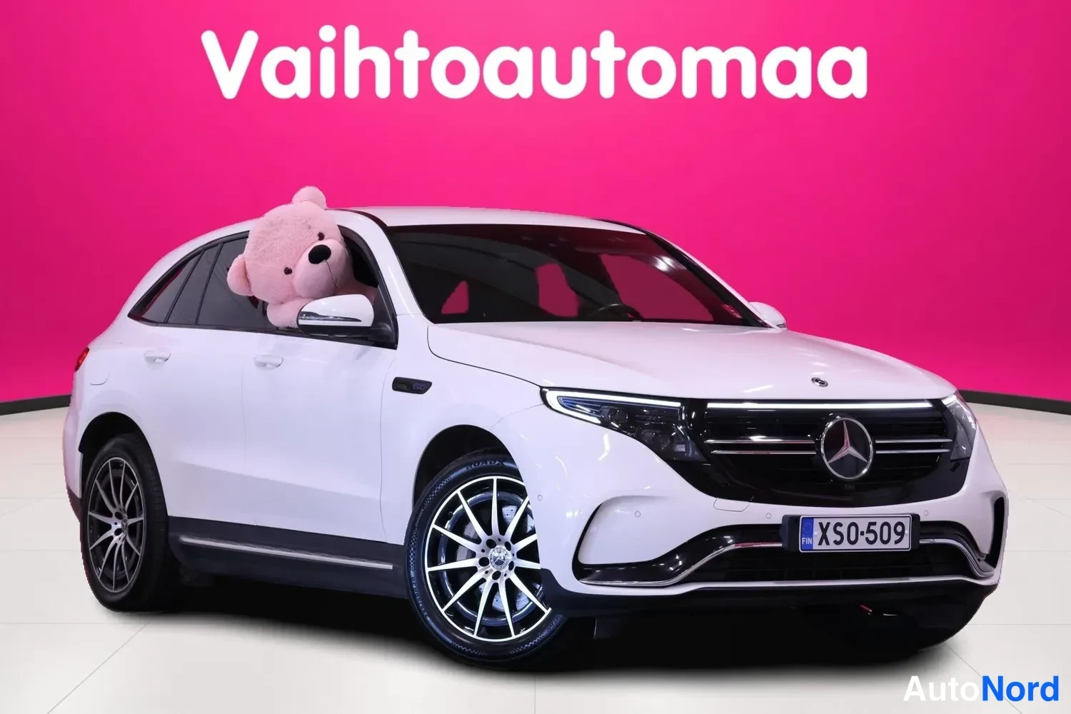 Etuviisto, nokka oikealle: Valkoinen Mercedes-Benz EQC edessä oikealta kulmasta, rekisteritunnus XS0-509, tumma etusäleikö ja poikittainen LED-päiväajovalo.