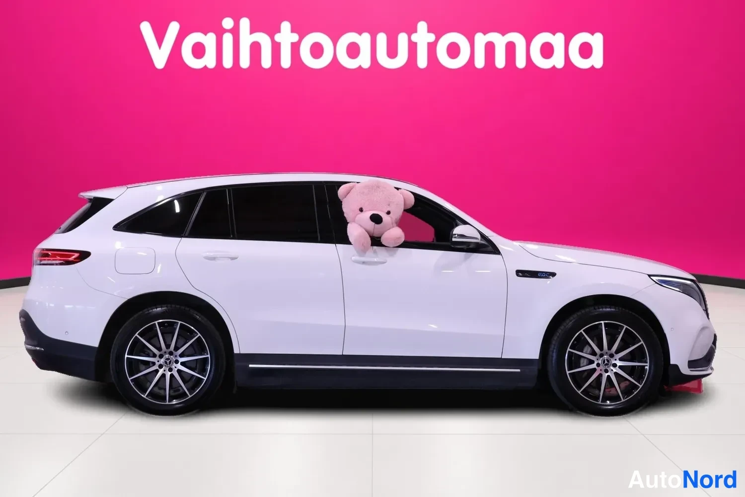 Etuviisto, nokka oikealle: Valkoinen Mercedes-Benz EQC sivuprofiilissa oikealta, etuvalo näkyy kuvan oikeassa reunassa, alumiinivanteet.