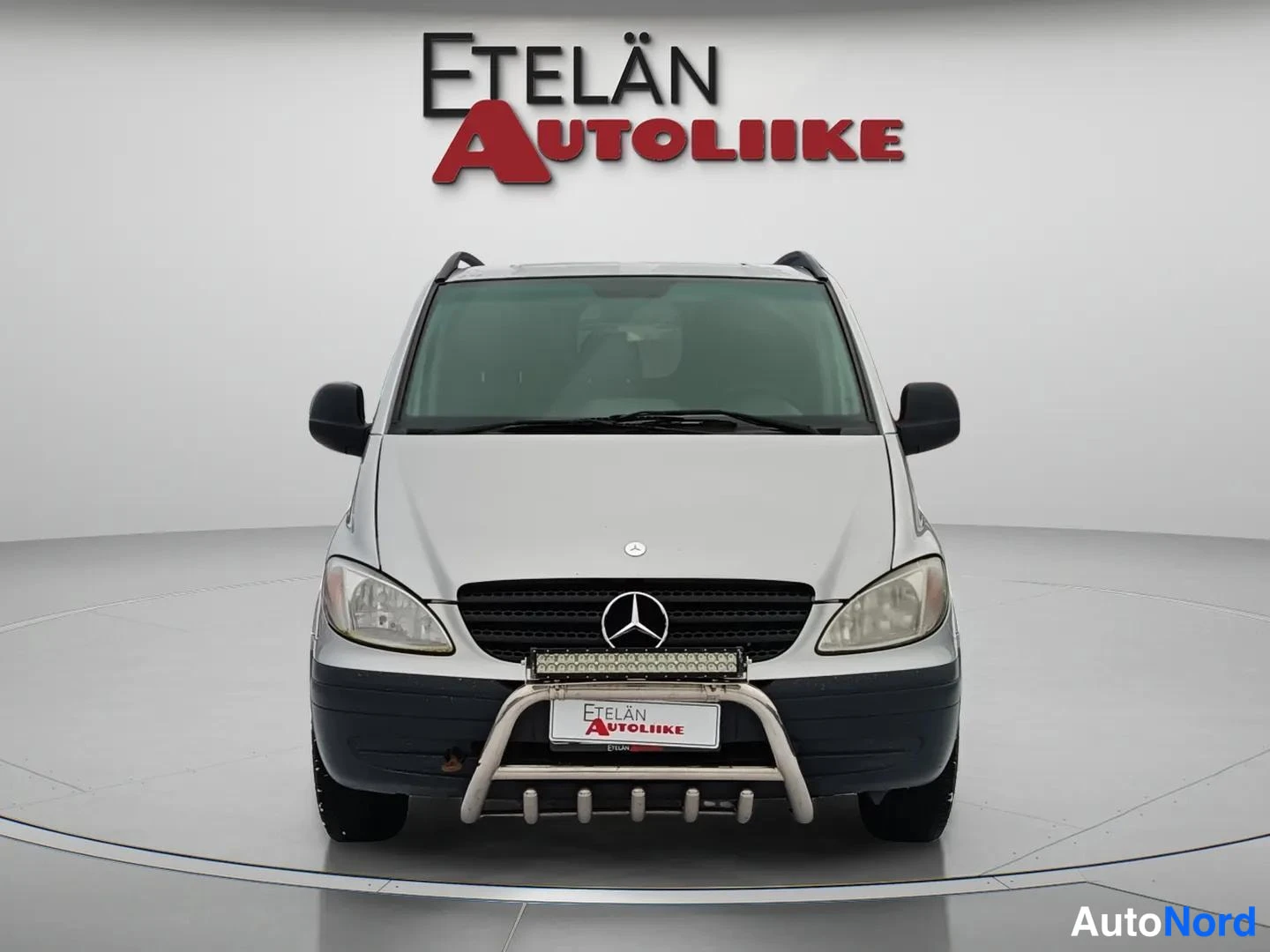 Edestä: Hopeinen Mercedes-Benz Vito suoraan edestä kuvattuna; etusäleikkö ja Mercedes-tähti sekä etupuskurin metallisuoja ja lisävalo näkyvät.