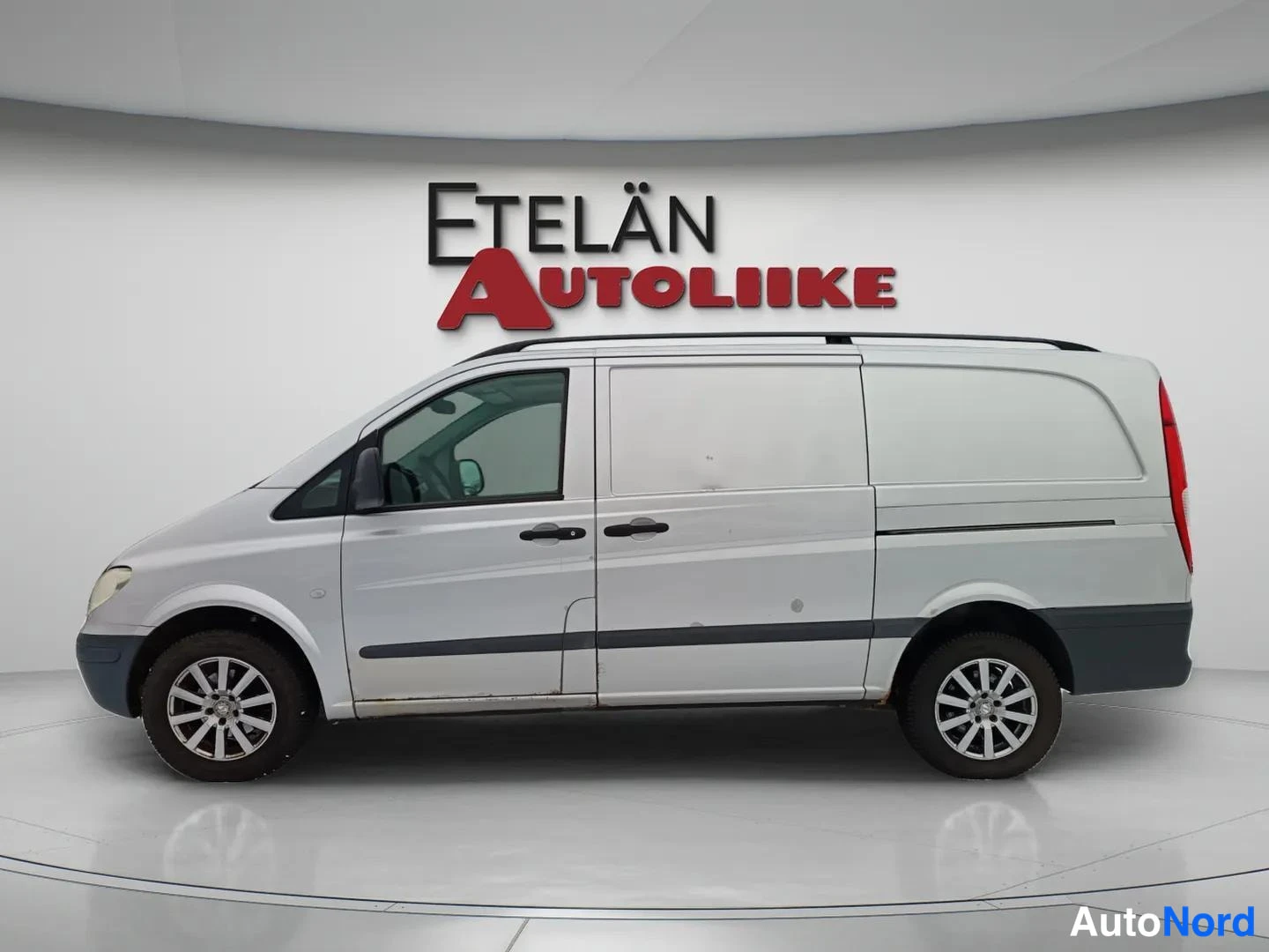 Sivulta: Mercedes-Benz Vito sivusuunnasta vasemmalta kuvattuna; hopeinen kuljetuspakettiauto, jossa kattotelineet ja takaovi. Vasen kylki ja pyörät näkyvät.