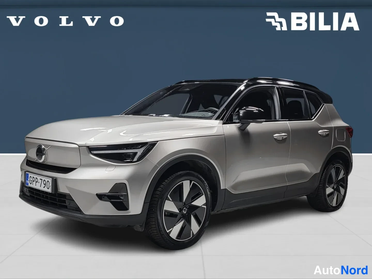 Etuviisto, nokka vasemmalle: Auton etukulma vasemmalta: hopeanbeige Volvo XC40, rekisteritunnus, musta lasikatto, studio.