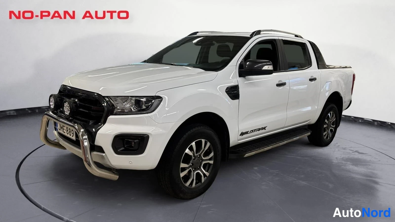 Etuviisto, nokka vasemmalle: Valkoinen Ford Ranger Double Cab -nalertti etukulmasta; edessä metri.jarvi-kaari ja lisävalot