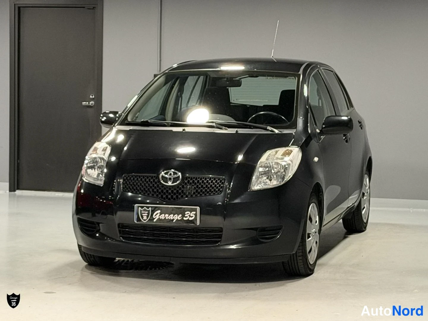 Musta Toyota Yaris 2006, etuviisto, keula vasemmalle, kuva 2