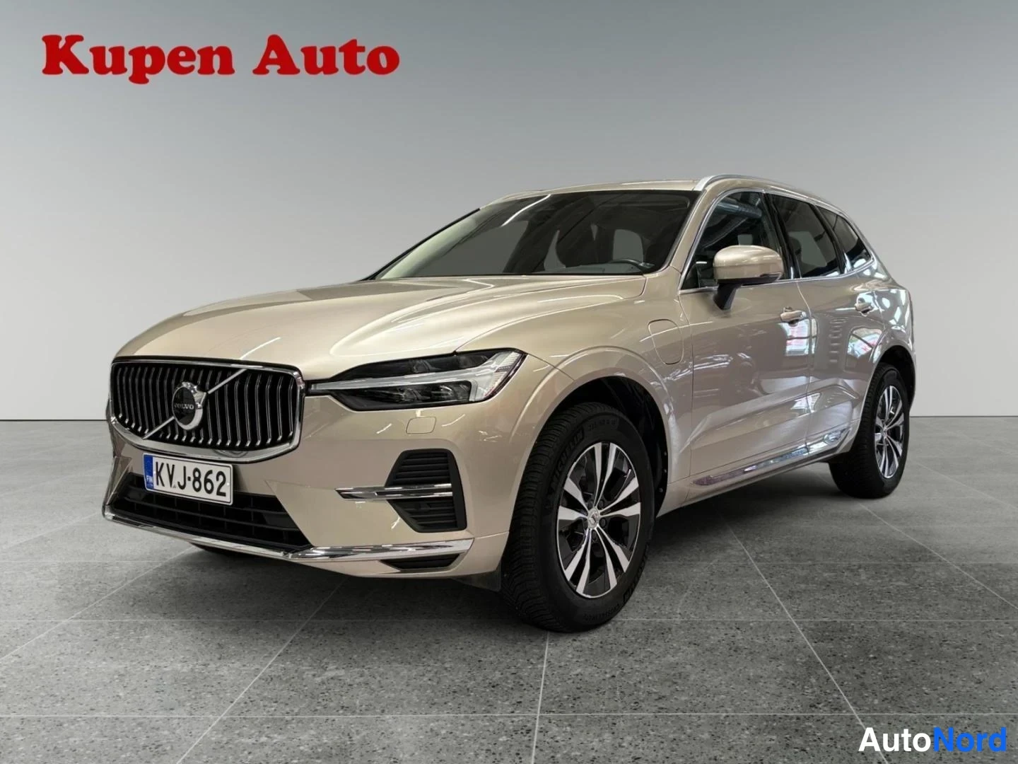 Etuviisto, nokka vasemmalle: Volvo XC60 -maastocurun edessä kolmeen neljäsosaan vaalean beigeasääriä auton keula vasemmalla ja kylki näkyvissä studiossa.