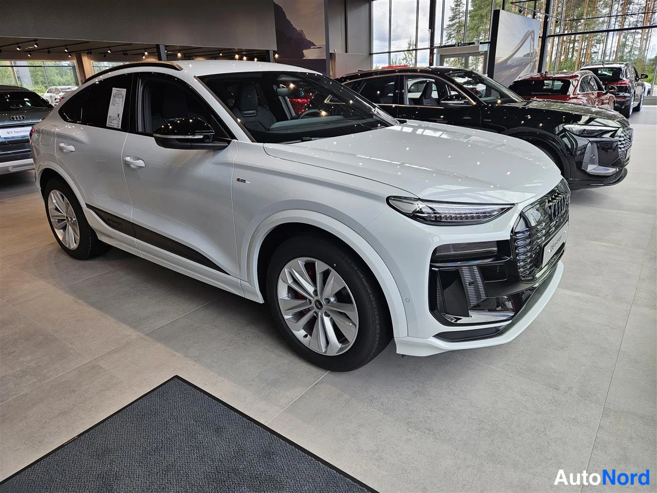 White Audi Q6 e-tron 2026, front three-quarter, nose to the right, photo 3
